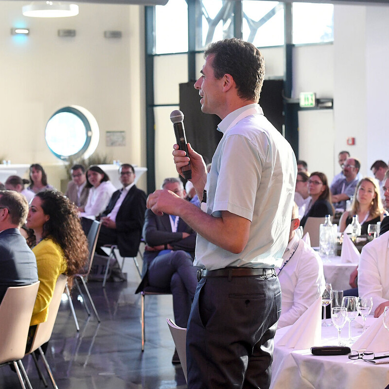 Vortragender mit Mikrophon auf der Bühne