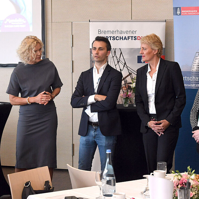 Redner und Moderatorin stehen gemeinsam auf der Bühne